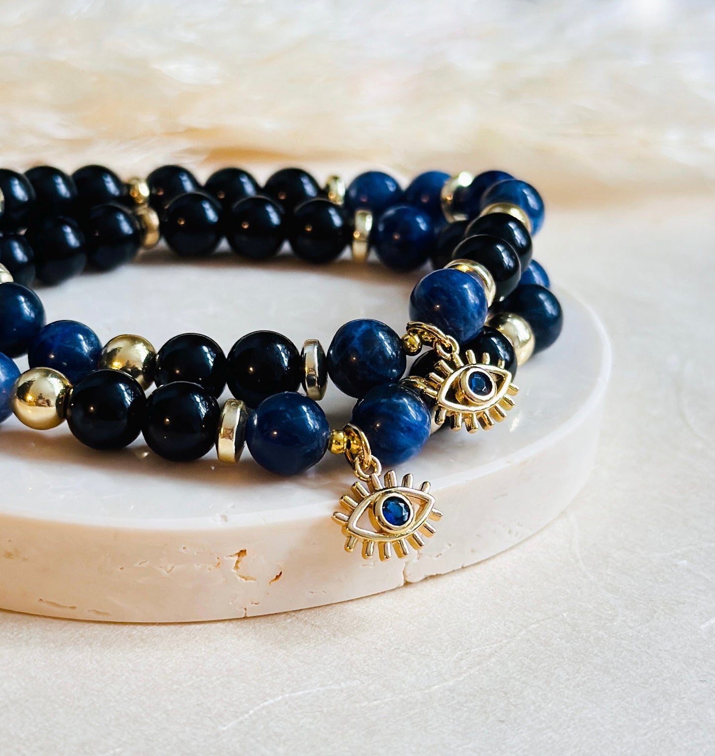 This exquisite gemstone bracelet blends the unique energies of Sodalite and Onyx, accentuated by an intriguing evil eye charm.