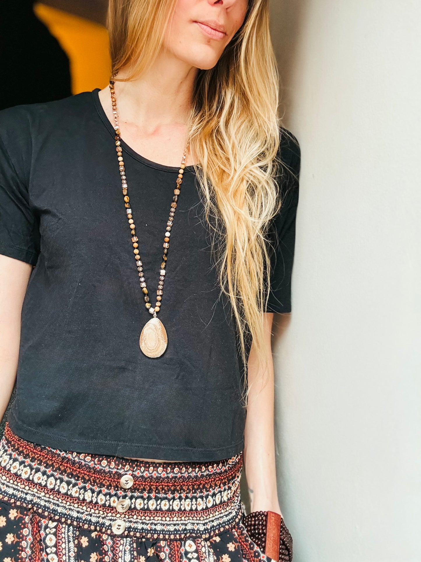 A boho-style necklace named The Isolde, crafted with warm Sandstone Jasper, shimmering gold and bronze glass beads, and a striking Sandstone Jasper pendant. Its earthy tones and natural textures evoke the strength of the earth and the magic of ancient landscapes. A symbol of resilience and wisdom, this handcrafted piece reflects nature’s quiet beauty.