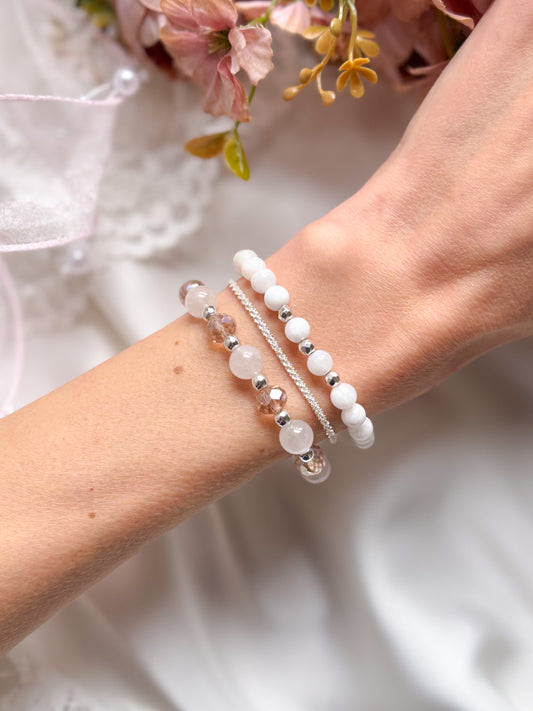 Close-up of a wrist wearing multiple beaded bracelets with a blurred floral background