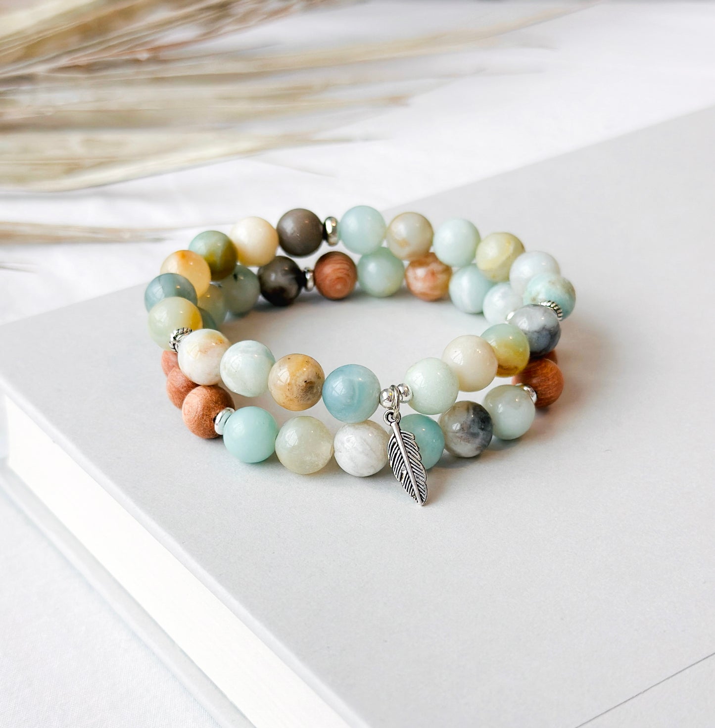 This healing gemstone bracelet stack is crafted with natural Amazonite beads and feather charm. Amazonite is known for its soothing energy, promoting calm and tranquility, and is believed to help balance the emotions, reduce stress and anxiety, and enhance communication. Amazonite brings clarity, balance and insight and is soothing to the nerves.
