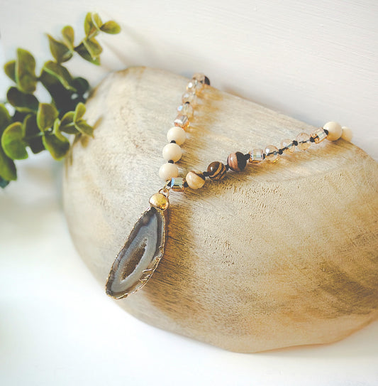 "The Arlo" gemstone necklace, a masterpiece that merges the grounding essence of River Stone Jasper gemstones, the delicate charm of glass beads, and the captivating allure of a Druzy Agate pendant.