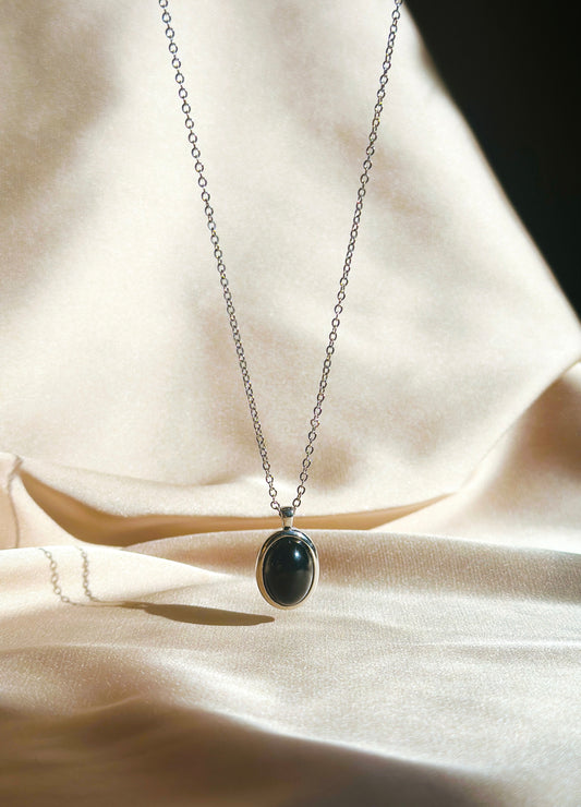 A sterling silver necklace featuring a polished Onyx charm. The deep black Onyx gemstone is known for its healing properties, offering strength, protection, and emotional balance. The necklace’s sleek sterling silver chain complements the onyx, creating an elegant, timeless accessory.