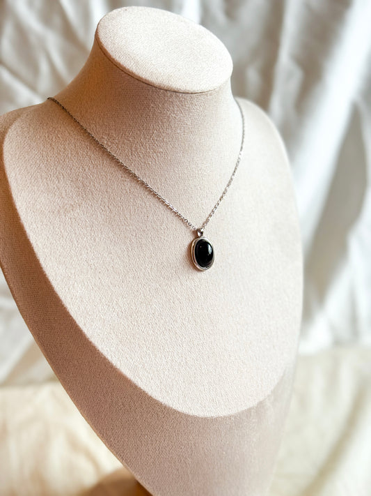 A Sterling Silver necklace featuring a polished black Onyx charm. The deep black gemstone is known for its healing properties, promoting strength, protection, and emotional balance. Paired with a sleek Sterling Silver chain, this elegant accessory blends style with holistic well-being.