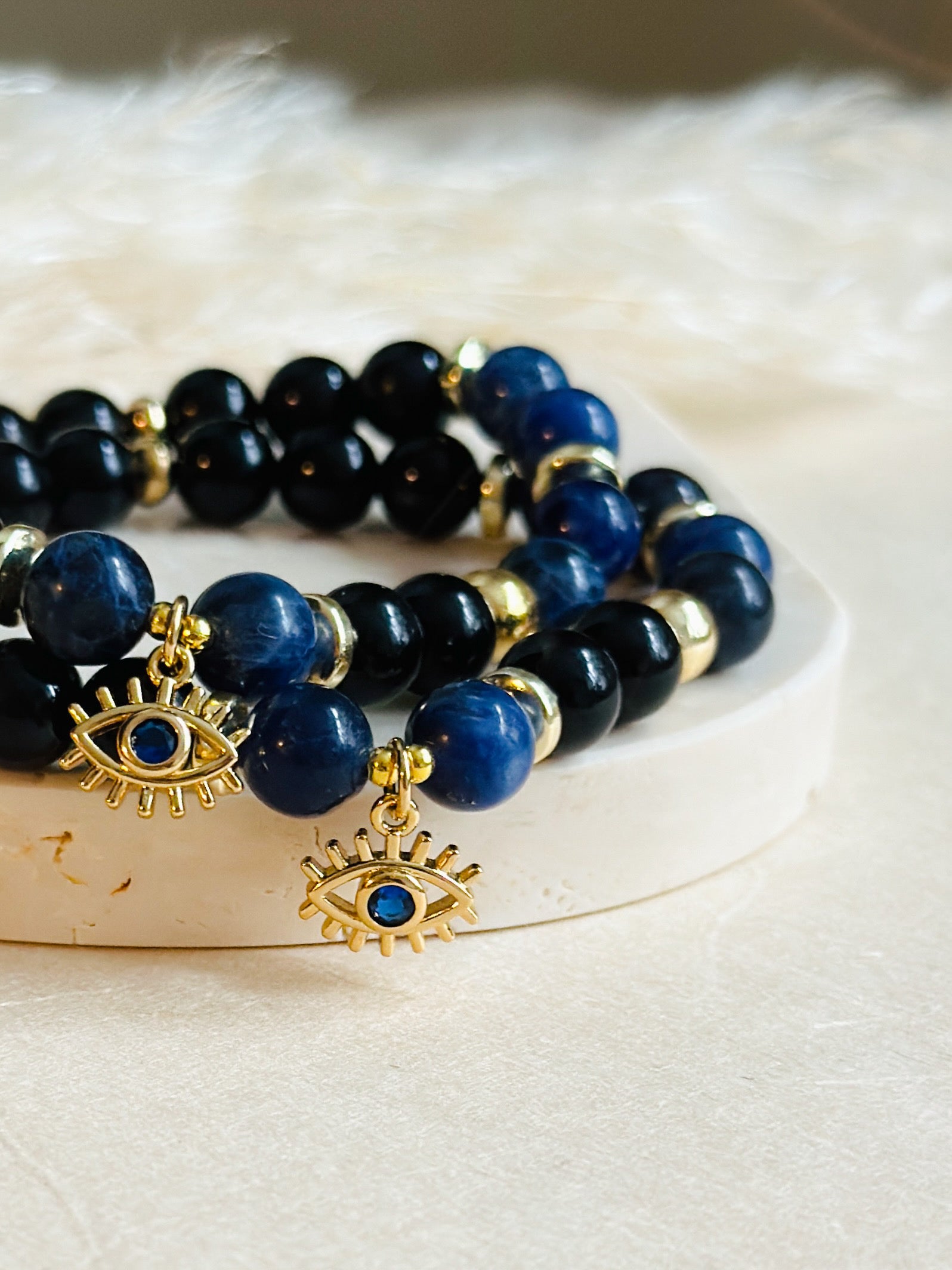 This exquisite gemstone bracelet blends the unique energies of Sodalite and Onyx, accentuated by an intriguing evil eye charm.