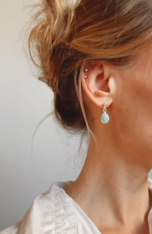 The Baya Earrings, crafted from exquisite sterling silver, showcase the timeless beauty of tear-drop-shaped Aquamarine gemstones. Aquamarine, with its serene blue hues reminiscent of the ocean, is used to inspire calmness and clarity.