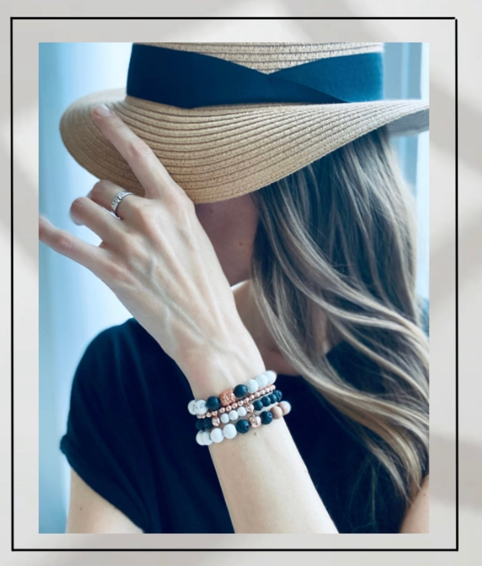 Model wearing neutral gemstone stacking bracelets created with Lava Rock, Howlite and Rosewood for calming and energy grounding 