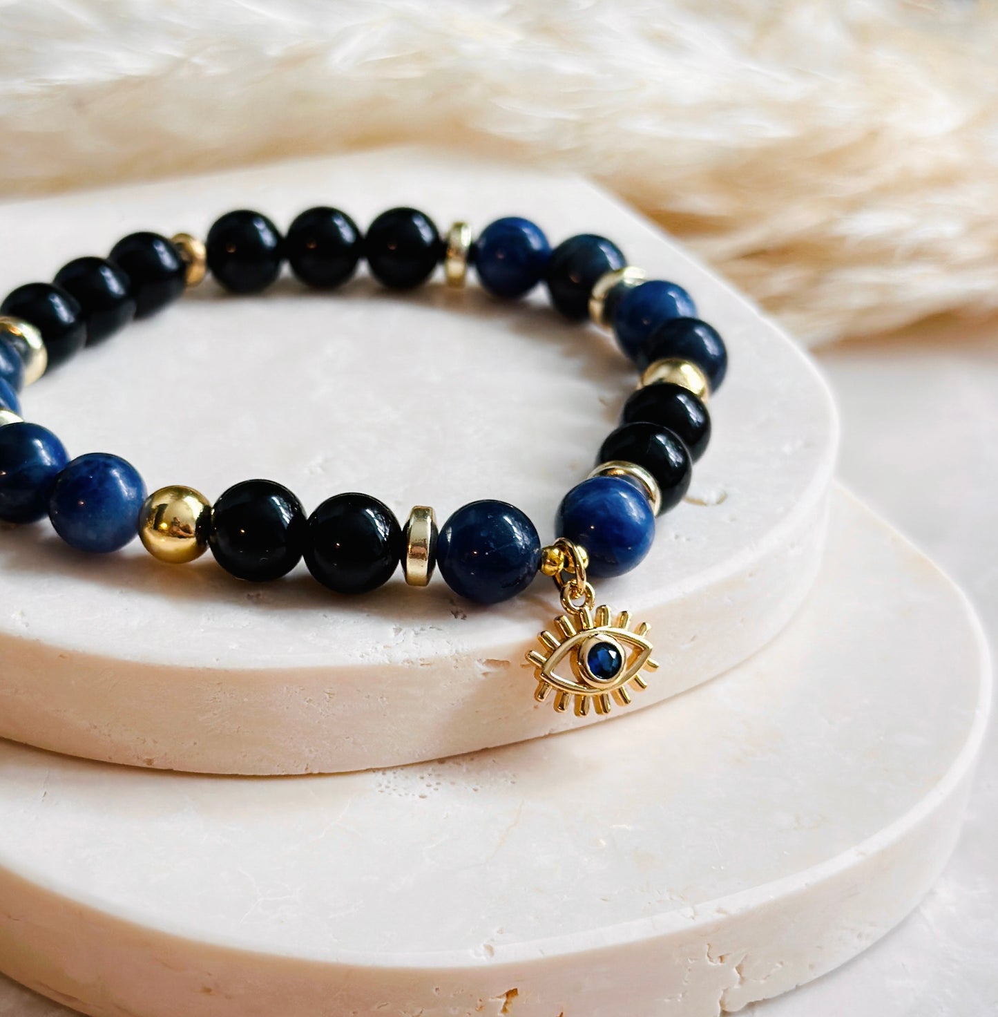 This exquisite gemstone bracelet blends the unique energies of Sodalite and Onyx, accentuated by an intriguing evil eye charm.