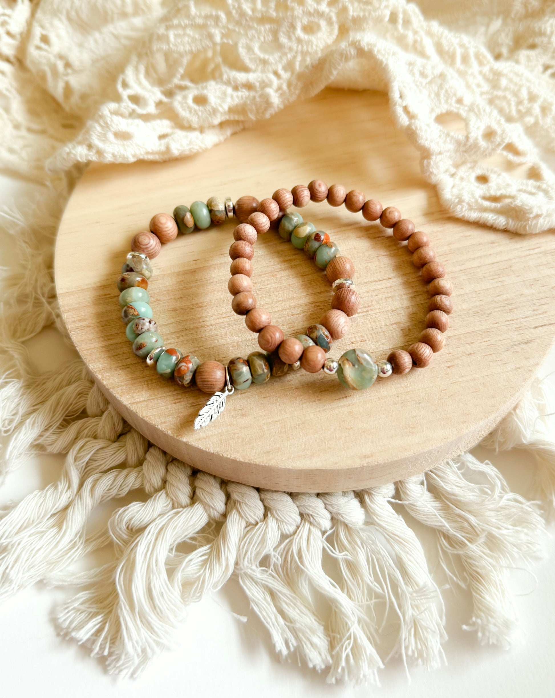 A handcrafted bracelet set featuring Serpentine Jasper beads in earthy green tones, symbolizing transformation and inner peace. Warm, natural Rosewood beads provide grounding energy, while a delicate feather charm dangles, representing freedom and intuition. Designed for free spirits and wanderers, this set embodies balance, resilience, and adventure.