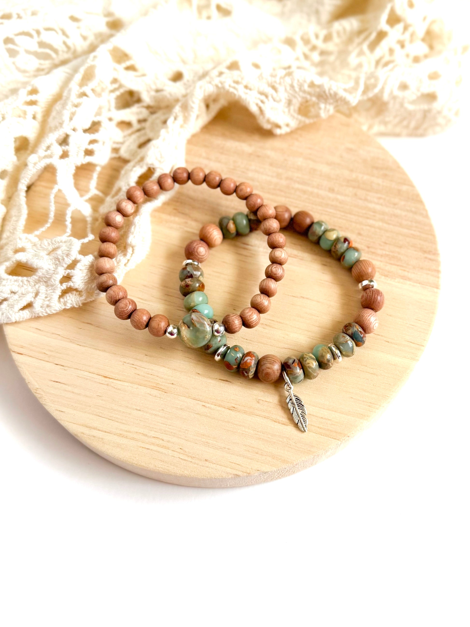 A handcrafted bracelet set featuring Serpentine Jasper beads in earthy green tones, symbolizing transformation and inner peace. Warm, natural Rosewood beads provide grounding energy, while a delicate feather charm dangles, representing freedom and intuition. Designed for free spirits and wanderers, this set embodies balance, resilience, and adventure.
