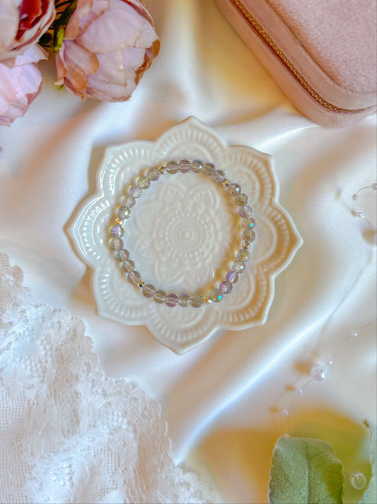 Decorative lace doily with a bracelet on a textured surface with flowers in the corner.