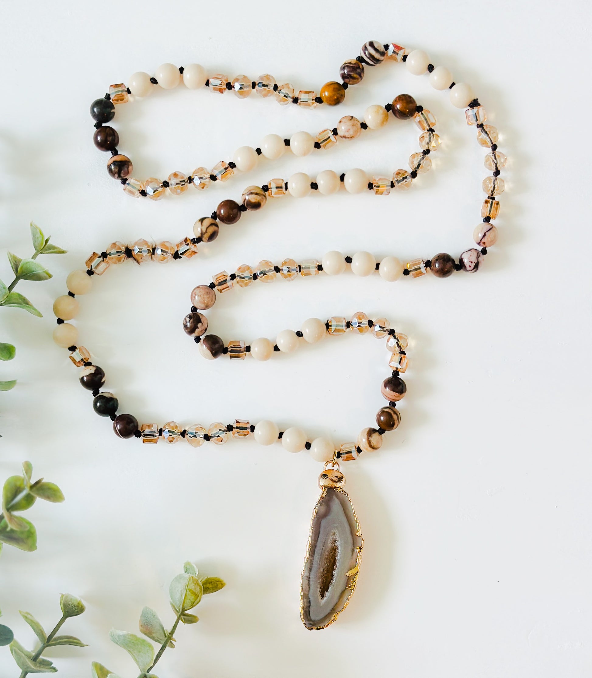 "The Arlo" gemstone necklace, a masterpiece that merges the grounding essence of River Stone Jasper gemstones, the delicate charm of glass beads, and the captivating allure of a Druzy Agate pendant. 