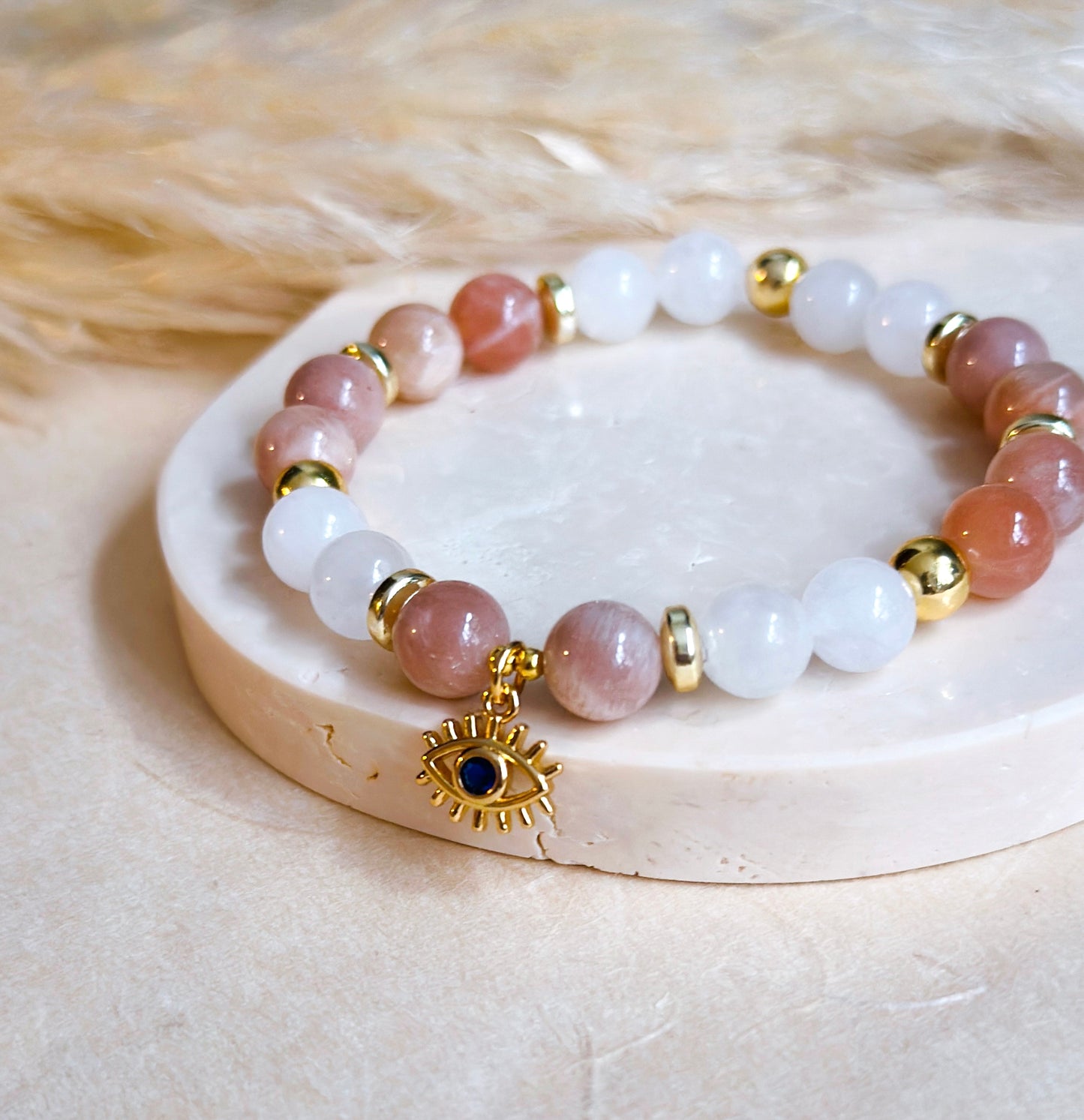 The “Elegant Guardian Bracelet" seamlessly weaves the healing properties of sunstone and white agate, accentuated by the watchful presence of an evil eye charm. 