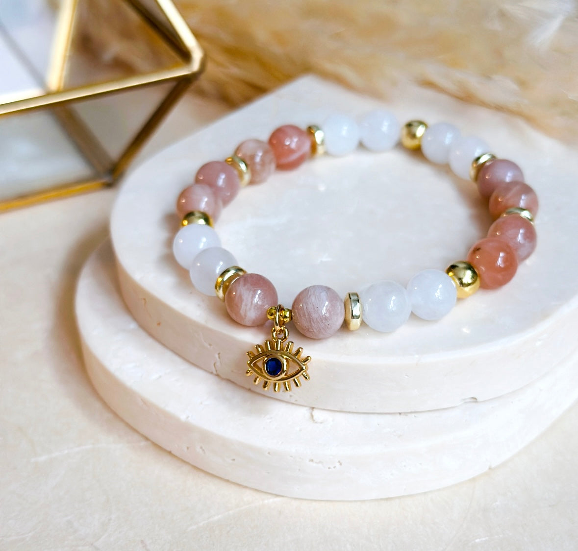 The “Elegant Guardian Bracelet" seamlessly weaves the healing properties of sunstone and white agate, accentuated by the watchful presence of an evil eye charm. 