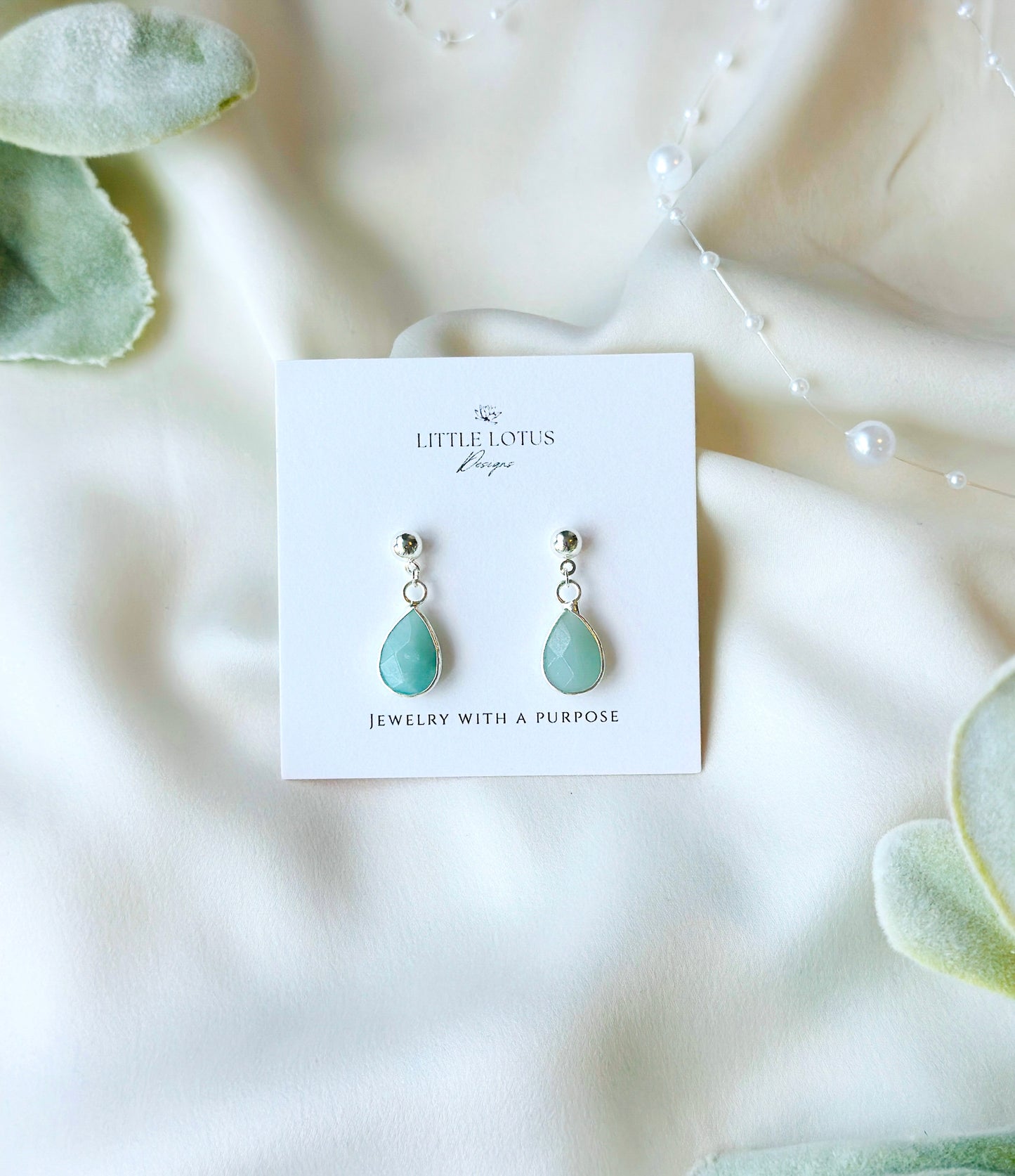 The Baya Earrings, crafted from exquisite sterling silver, showcase the timeless beauty of tear-drop-shaped Aquamarine gemstones. Aquamarine, with its serene blue hues reminiscent of the ocean, is used&nbsp;to inspire calmness and clarity.