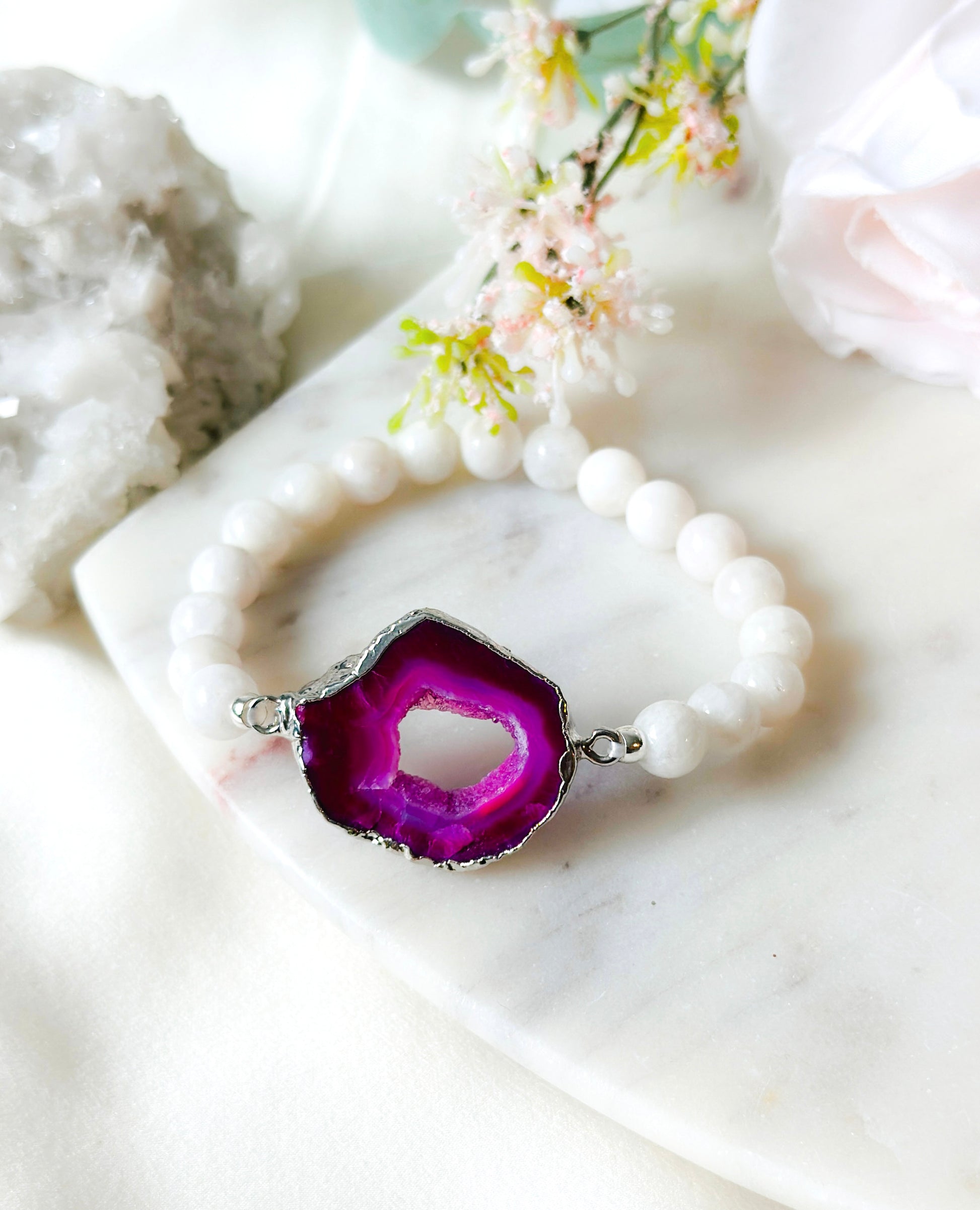 Introducing our "Magenta Moonlight Bracelet," a stunning fusion of beauty and healing. This bracelet features a centerpiece adorned with a mesmerizing fuchsia Druzy agate connector, exuding a delicate charm and a touch of nature's artistry. The soft, rosy hues of the agate evoke feelings of love and tranquility.

