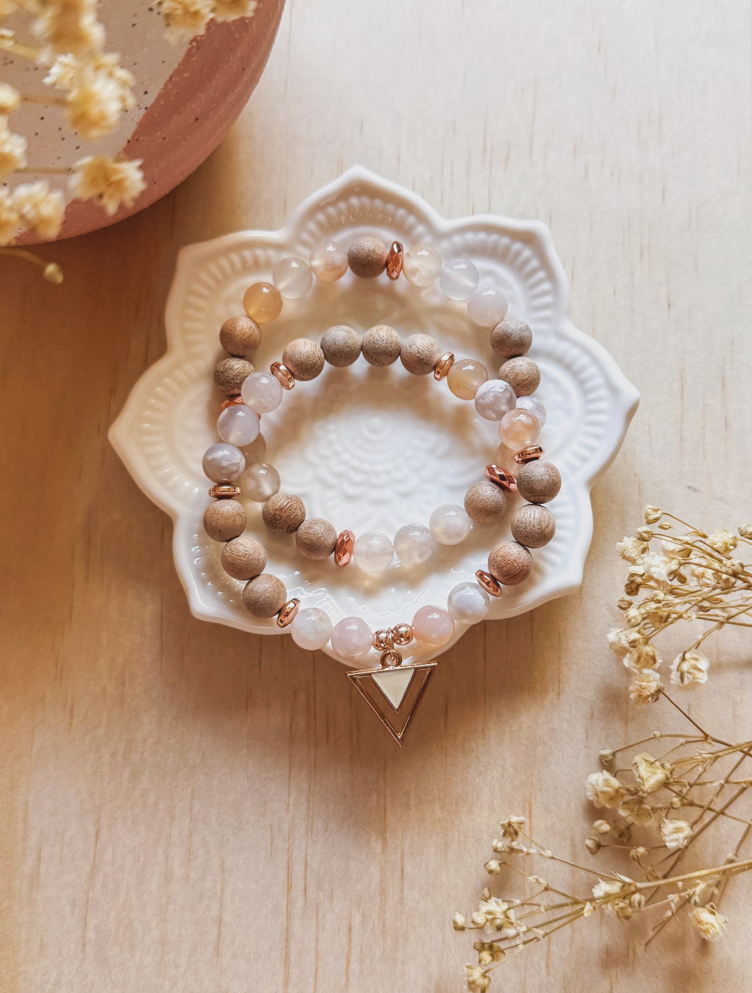 A delicate boho-style bracelet set called The Sakura Bracelet Set, featuring soft pink Flower Agate gemstones paired with light matte Beechwood beads. The bracelets are styled together, radiating a gentle, natural elegance inspired by spring blossoms. The overall aesthetic feels calming, feminine, and harmonious — symbolizing growth, grounding, and inner peace.