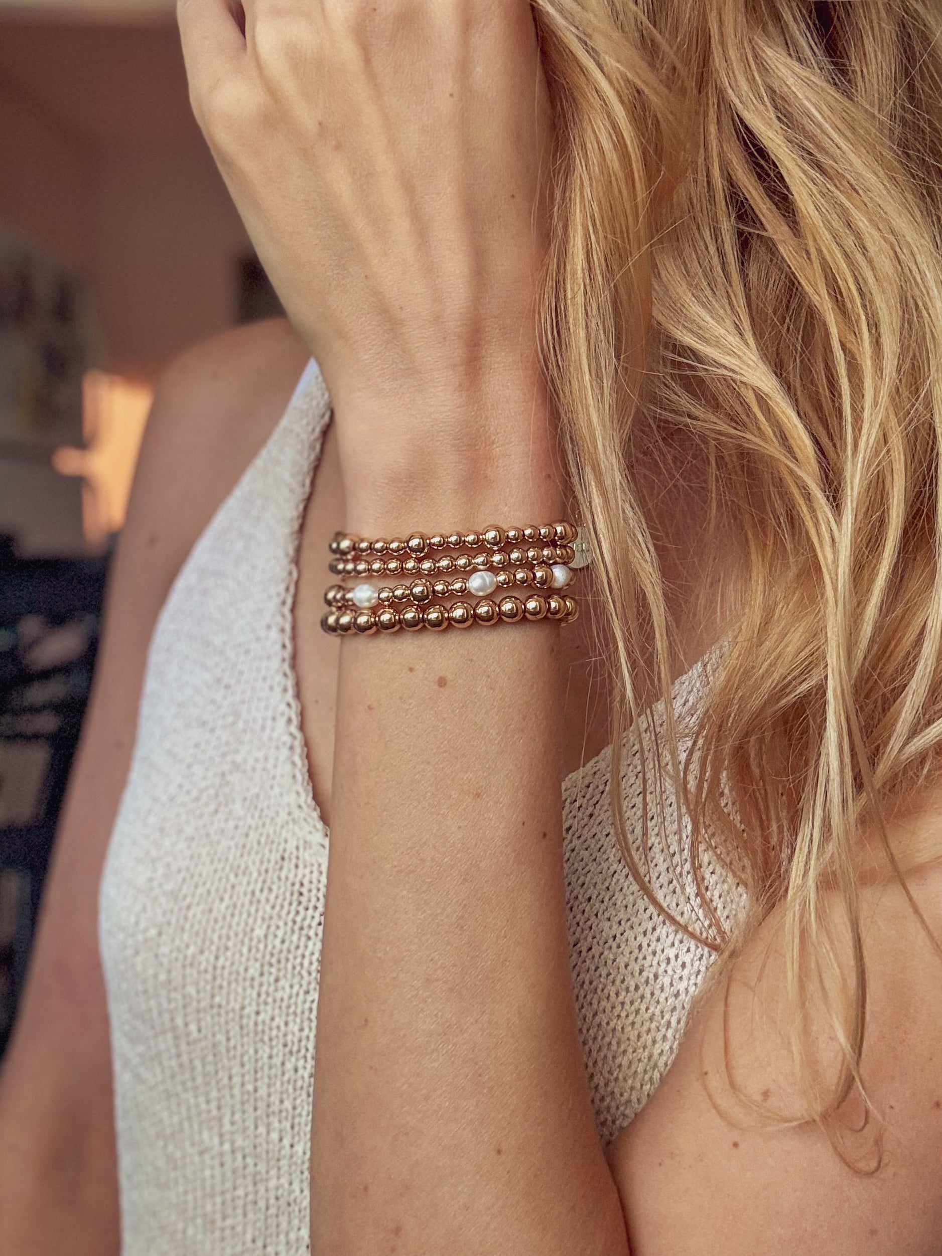 Close-up of a person wearing a rose gold bracelet on a blurred background