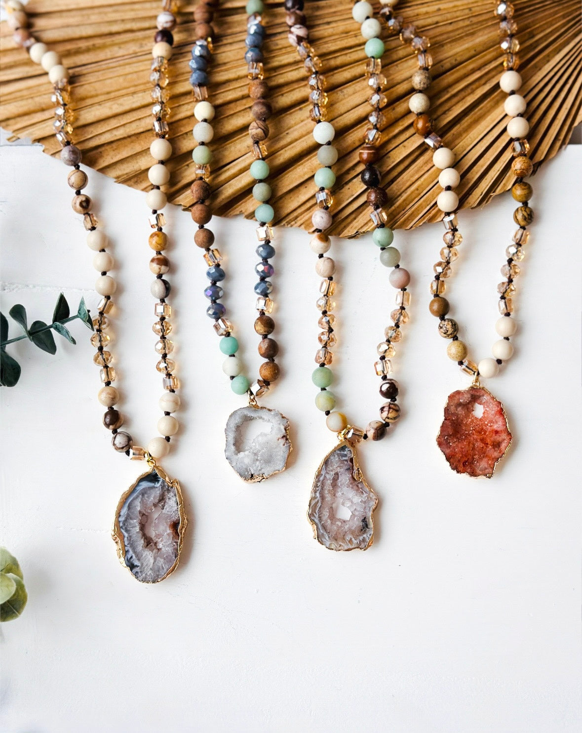 Set of beaded necklaces with geode pendants on a white background
