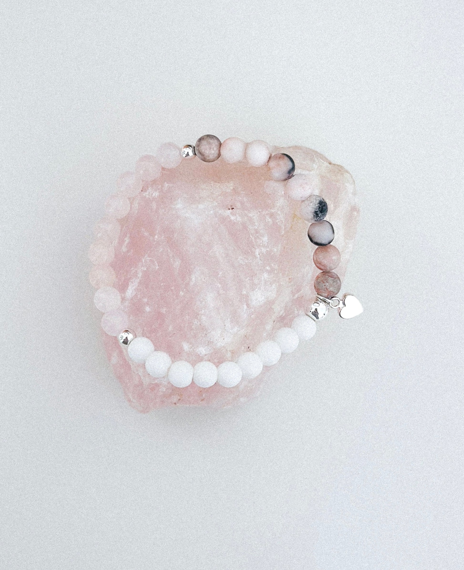This exquisite gemstone bracelet blends the soothing energies of frosted Pink Zebra Jasper, the love-infused essence of Rose Quartz, and the calming properties of white agate. Crafted with care, it features a delicate silver heart charm, adding a touch of elegance to its design.
