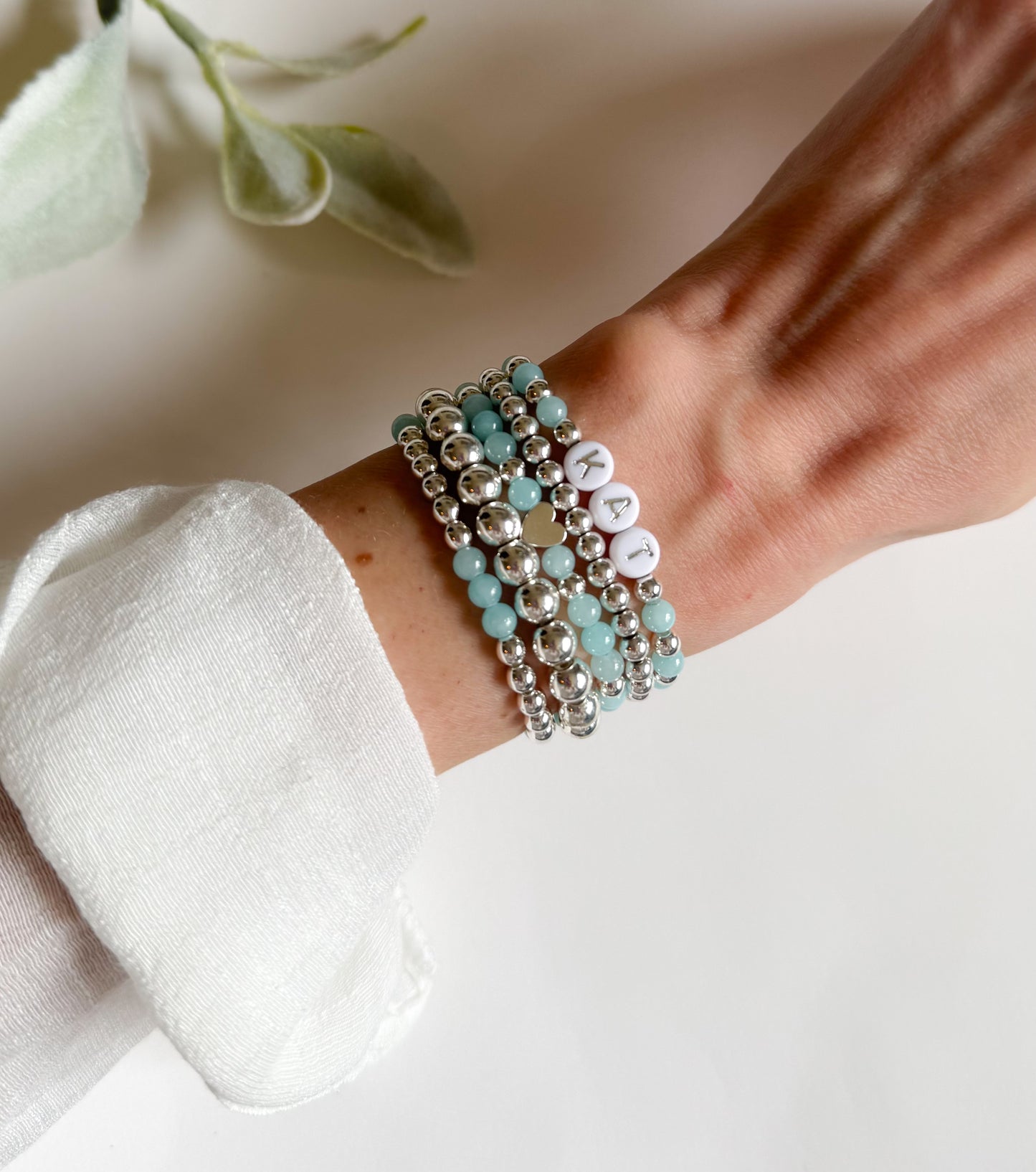 Dreamy bracelet stack featuring shimmering silver hematite and calming aquamarine beads, designed to soothe and center the spirit. Includes customizable silver letter beads for a personalized touch, symbolizing clarity, connection, and inner peace.
