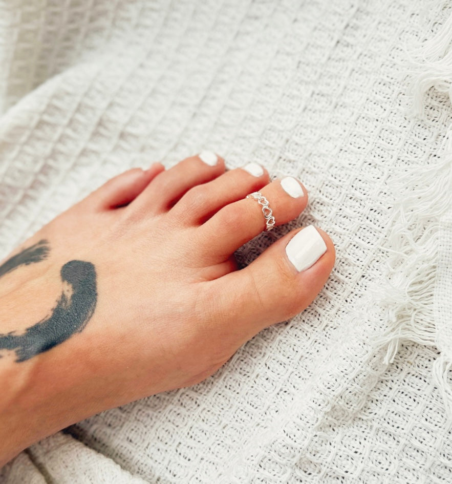 The Ocean Love Toe Ring, a sterling silver piece capturing the sea's essence and your affection. This adjustable heart-shaped toe ring blends elegance with beachy charm, perfect for ocean lovers and romantics.