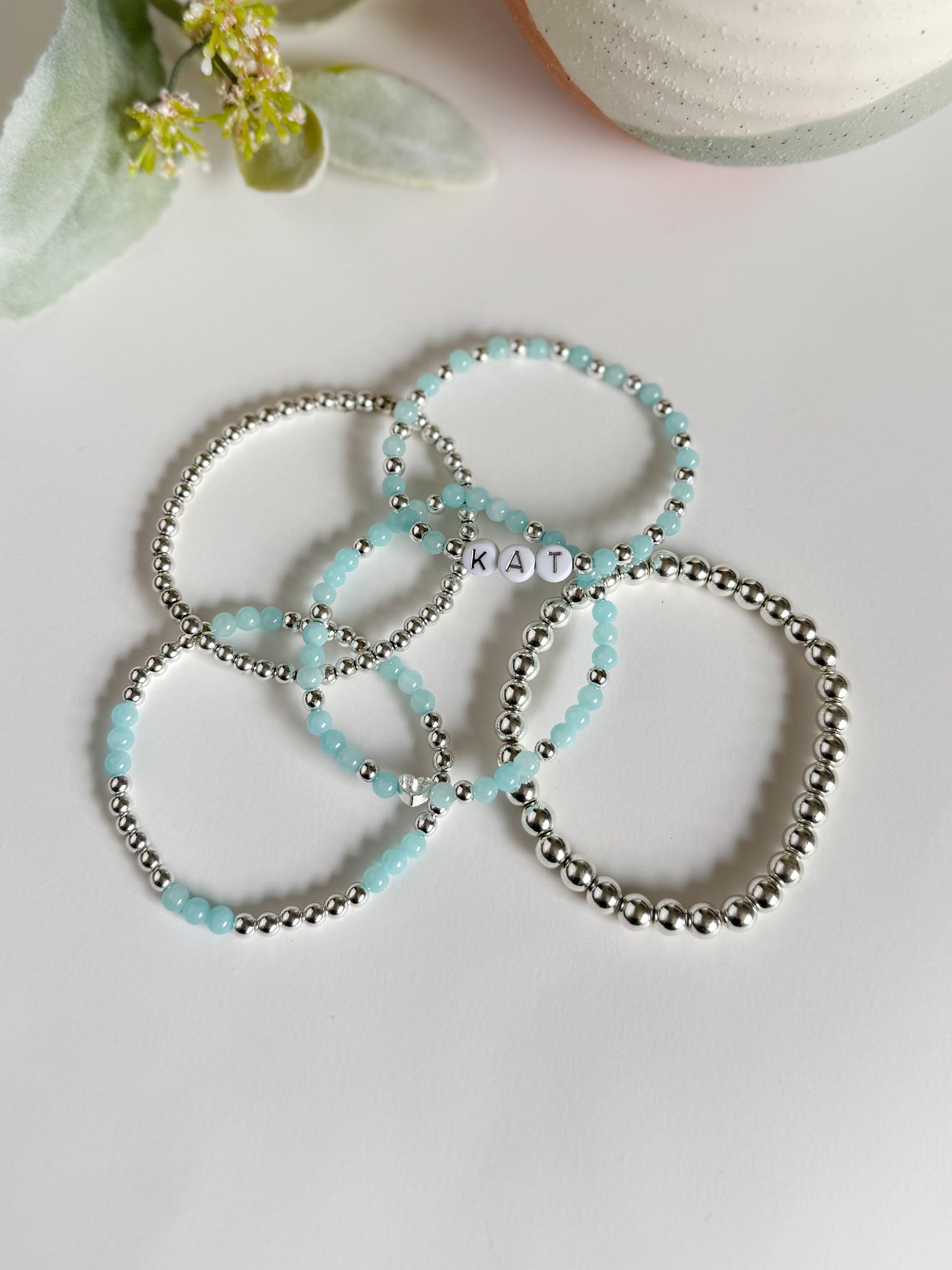 Dreamy bracelet stack featuring shimmering silver hematite and calming aquamarine beads, designed to soothe and center the spirit. Includes customizable silver letter beads for a personalized touch, symbolizing clarity, connection, and inner peace.
