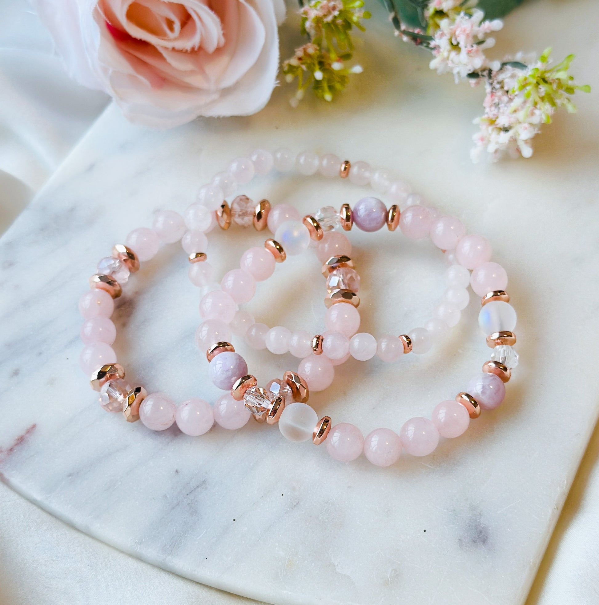 A gemstone bracelet set meticulously crafted with the soothing energies of Rose Quartz, the enchanting iridescence of Aura Quartz, the serene vibes of Kunzite, and the soft allure of pink glass beads.