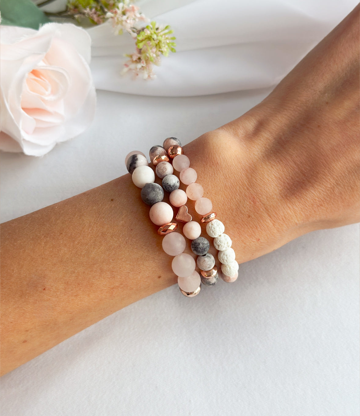 Elevate your senses with the ethereal "Zara Rose" gemstone bracelet stack, a divine fusion of Pink Zebra Jasper, frosted Rose Quartz, White Lava rock, and a delicate rose gold heart bead.