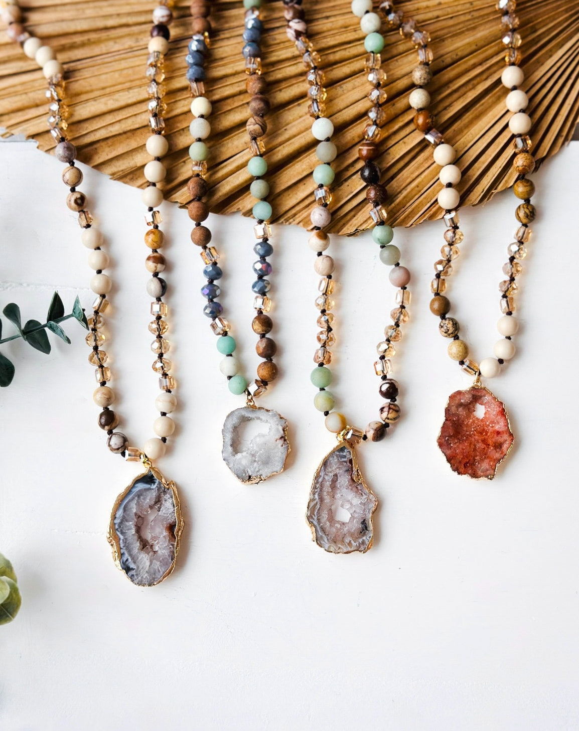Necklaces with geode pendants hanging against a textured surface