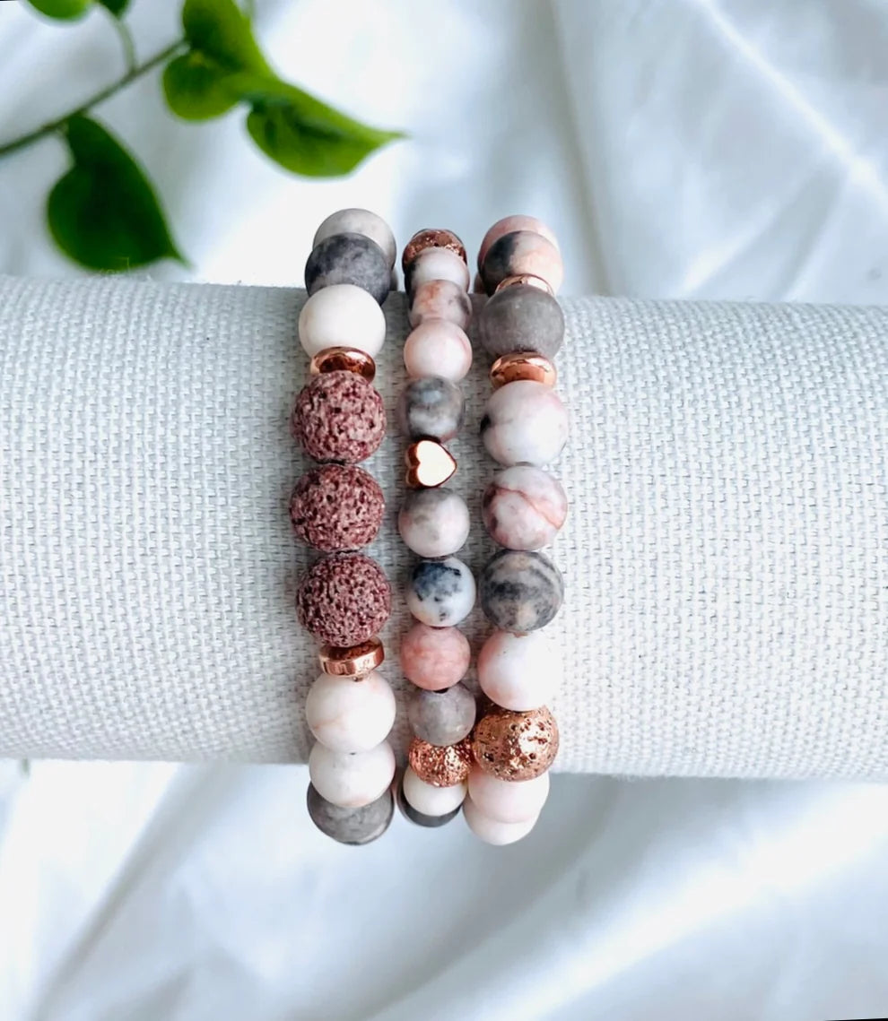 This beautiful gemstone bracelet set features Pink Zebra Jasper and Mauve Lava Rock beads. The Pink Zebra Jasper is a unique stone that is said to bring balance and stability to the wearer, as well as enhancing creativity and self-expression. Pink Zebra Jasper is known as the “supreme nurturer” and it said to help achieve a state of calm and zen. This is a calming, grounding gemstone that eases tension during difficult situations. 